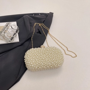 Detail of elegant pearl evening clutch bag with gold chain strap and snap closure