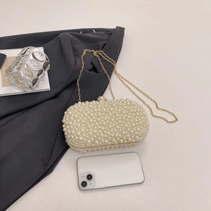 Detail of elegant pearl evening bag with gold chain strap and metallic clasp closure