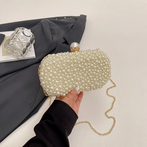 Detail of white handmade pearl evening clutch with gold chain and large pearl clasp