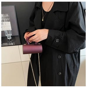 Close-up of a purple cylindrical acrylic evening bag with gold chain and top handle