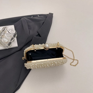 Detailed macro of hand-beaded white pearls on evening clutch with gold metal frame
