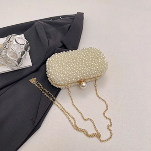 Close-up of pearl evening clutch with gold chain strap and large pearl clasp detail