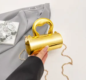 Detail showing high-gloss gold cylindrical handbag with unique handle and metal chain