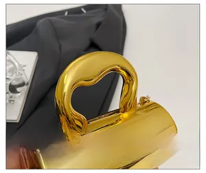 Macro shot of polished gold metallic handle and luxury chain detail on evening handbag