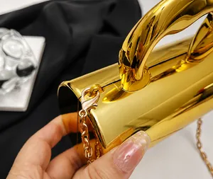 Detail of gold mirror handbag showing the metal ring handle and lobster clasp chain strap