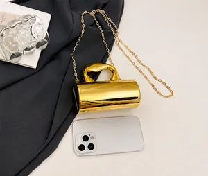 Detailed comparison of mini gold cylindrical handbag with smartphone for size scale
