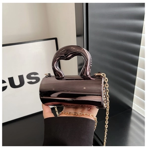 Detailed close-up of a mini cylindrical handbag with metallic chrome finish and gold chain