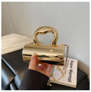 Detailed view of mini cylindrical gold metal handbag with artistic wavy handle and chain