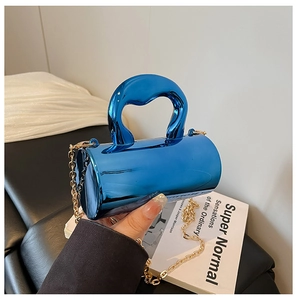 Close-up of elegant metallic blue mini cylinder handbag with gold chain strap detail