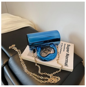 Close-up of royal blue metallic cylinder handbag with liquid metal handle and gold chain