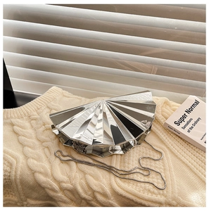 Detail of silver metallic fan-shaped evening clutch with sleek chain on knit background