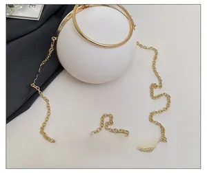 Detail of elegant white spherical evening bag with golden ring handle and chain strap