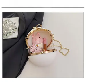 Interior capacity show of white round acrylic sphere bag with gold chain and cosmetics
