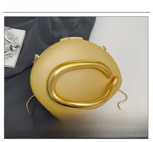 Close-up of matte gold hardware handle and chain strap on women's evening box clutch bag