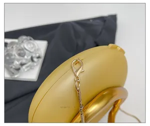 Macro detail of the golden snake chain and lobster clasp on a yellow acrylic box bag