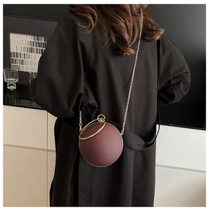 Fashionable round spherical handbag with gold ring handle and metal chain strap