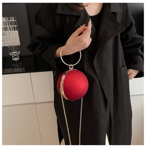 Macro detail of red spherical evening bag with matte texture and gold metal ring handle