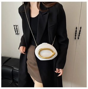 Detail of white asymmetric acrylic clutch with gold metal accent and chain strap