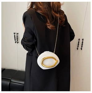 Detail view of white pebble-shaped crossbody bag with large gold metal loop and chain