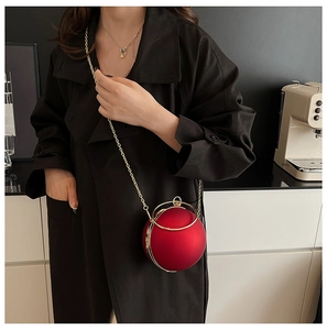Close-up of a red spherical evening clutch bag featuring a gold ring handle and chain strap