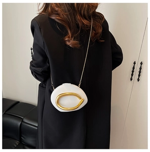 Detail of white sculptural clutch bag with large gold metal ring and chain strap