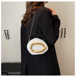 Detail of white egg-shaped acrylic clutch with large gold metal ring handle and chain