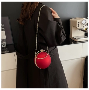Macro detail of red spherical evening bag with golden circular handle and chain strap