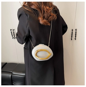 Detail of artistic pebble-shaped crossbody bag with gold metal ring and chain