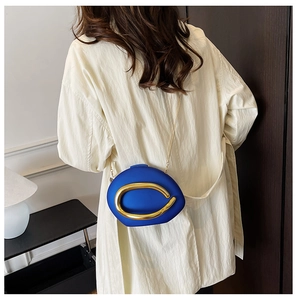 Detail of royal blue geometric crossbody bag with a large gold oval metal buckle and chain