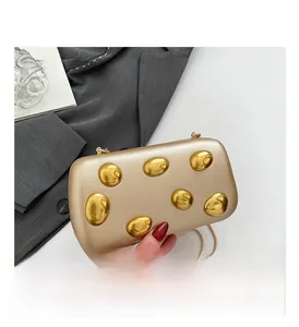 Detailed macro view of champagne gold evening clutch with metallic beads and chain strap
