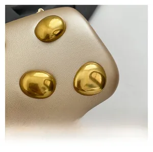 Macro view of pebbled leather texture and polished pebble-shaped golden metal hardware