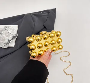 Detailed view of luxury gold metal hard shell clutch bag with spherical 3D texture