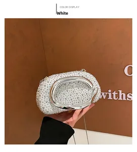 Détail de la pochette ovale blanche ornée de strass argentés et poignée en C en métal