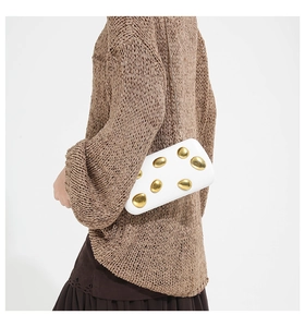 Detailed view of white rectangular clutch with irregular gold metallic pebble texture