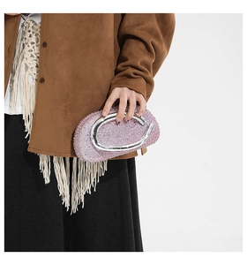 Détail d'une pochette ronde en strass rose avec une large poignée anneau en métal argenté