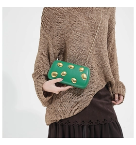 Detail view of a green leather clutch with gold pebble metal accents and chain strap