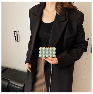 Close-up of mint green acrylic clutch bag with 3D spherical texture and golden chain