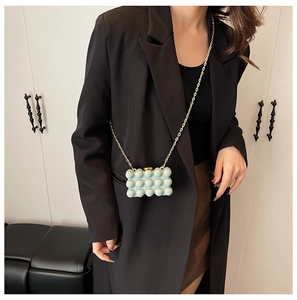 Detail of mint green mini bubble bag with a gold chain strap on a chic model outfit