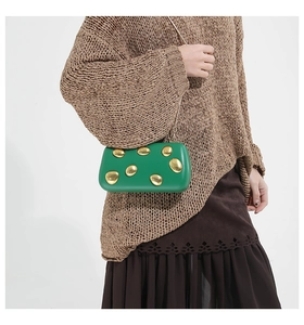 Green leather evening clutch with metallic gold accents and a chain strap shown on a model