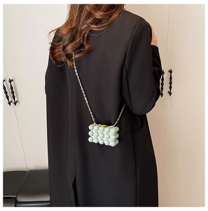 Detailed close-up of mint green bubble texture mini bag with gold chain strap worn on back