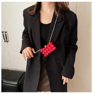 Mini red box bag with bubble texture and gold chain on a black blazer outfit