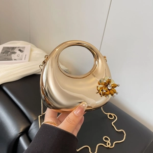 Close-up of golden mirror clutch bag with crystal flower and hollow round handle