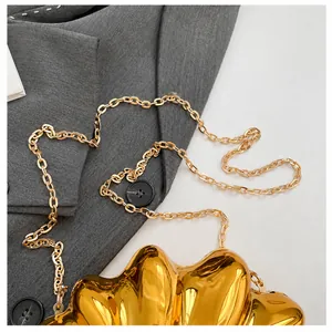 Detail of elegant gold metal shell clutch showing the polished chain strap and glossy finish