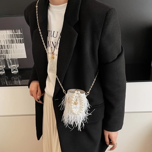 Close-up of white feather bucket bag with pearl handle and golden chain on a model