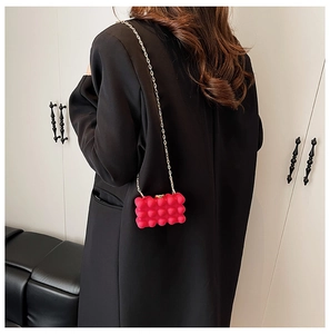 Detail of rose pink bubble texture mini bag with gold chain strap on black blazer