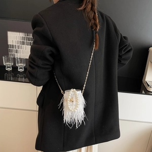 Detailed view of white ostrich feather bucket bag with pearl handle and gold chain strap
