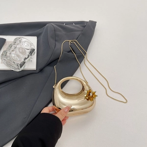 Detail of gold moon clutch bag with amber crystal flower and ring handle on grey blazer