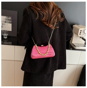 Detail of pink metallic crossbody bag with gold chain and beaded handle on model