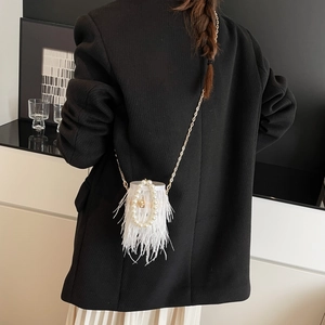Detailed view of white feather crossbody bag with pearl handle and golden chain strap