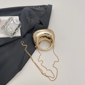 Detail of a gold egg-shaped acrylic evening bag with a circular handle and chain strap